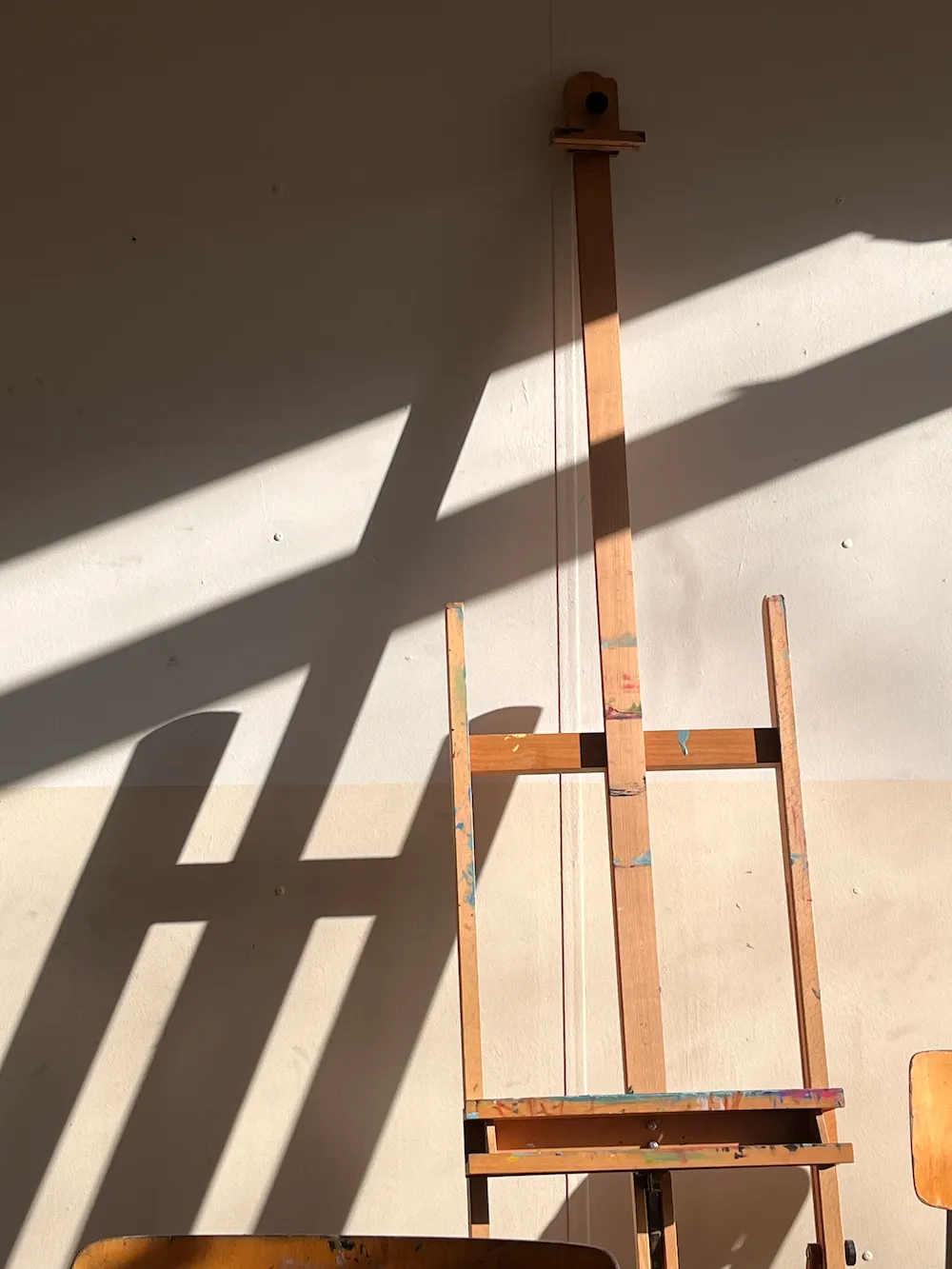Houten schildersezel met verfspetters in kunstenaarsstudio zonlicht - traditionele kunst atelier atmosfeer